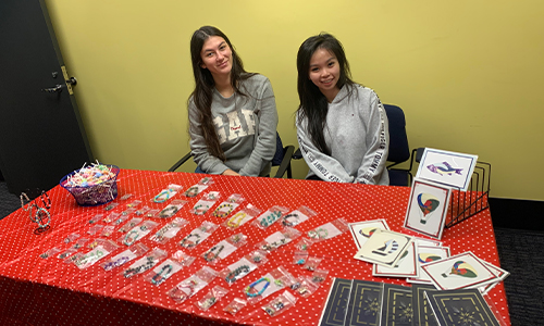 Two women from JWU seated at a fundraising table