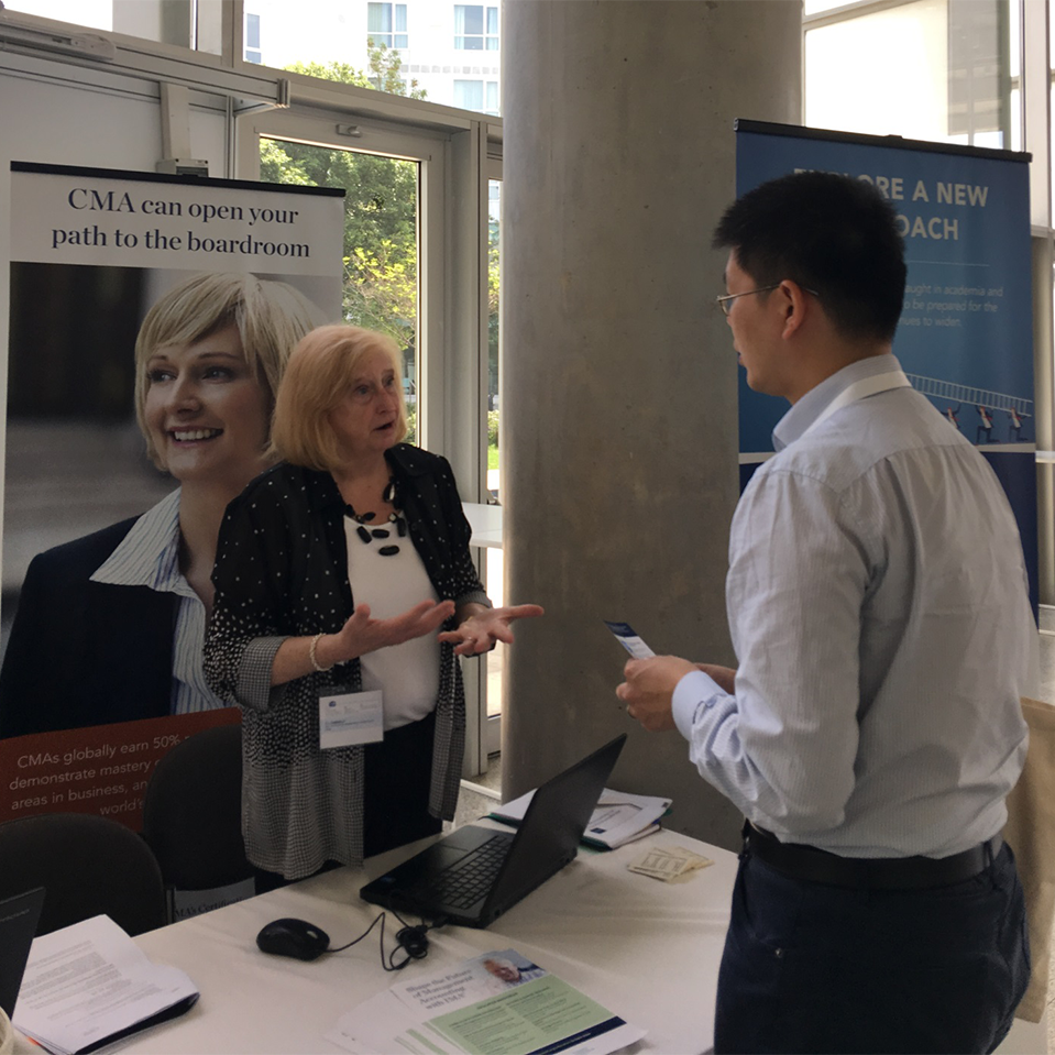 CJ McNair-Connolly at IMA booth talking with Michael Tse, Head of Accounting from the Holmes Institute, Australia