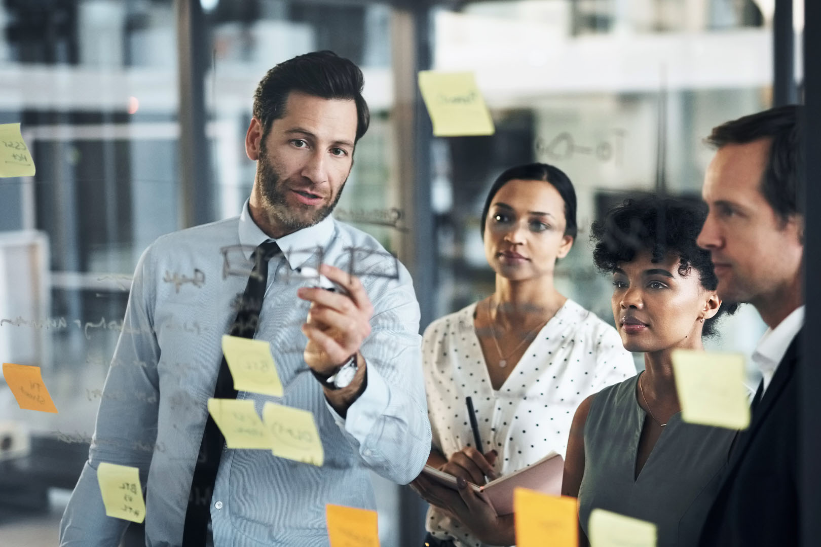 A financial professional writing on a clear markerboard