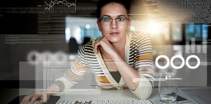 A woman seated at a desk using a mouse and keyboard