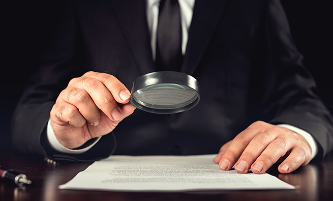 Person looking at a paper with magnifying glass