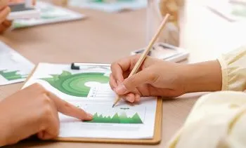 A view of a report on a table with two hands working on the report