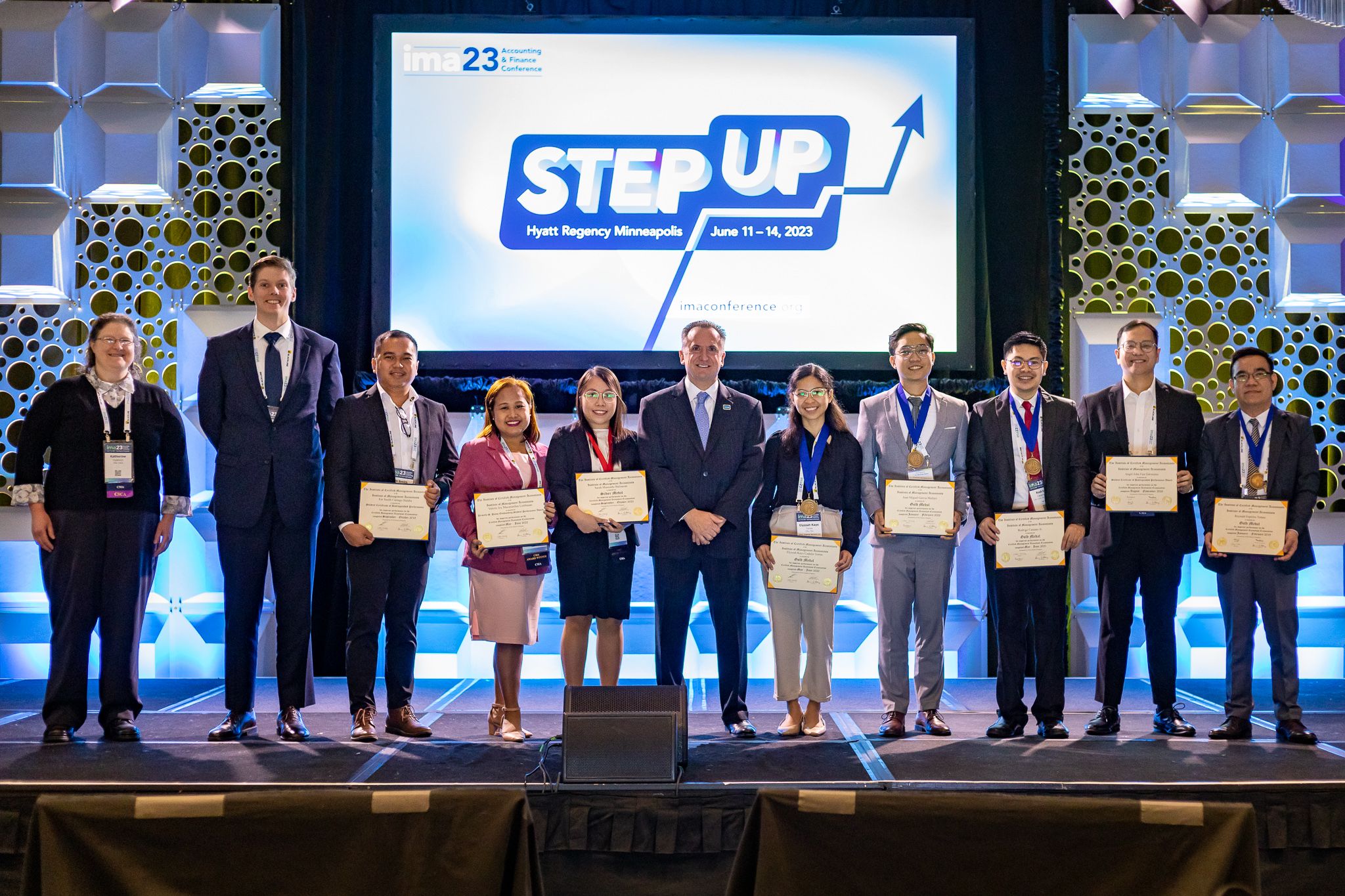 Mike DePrisco stands on stage with award winning IMA members