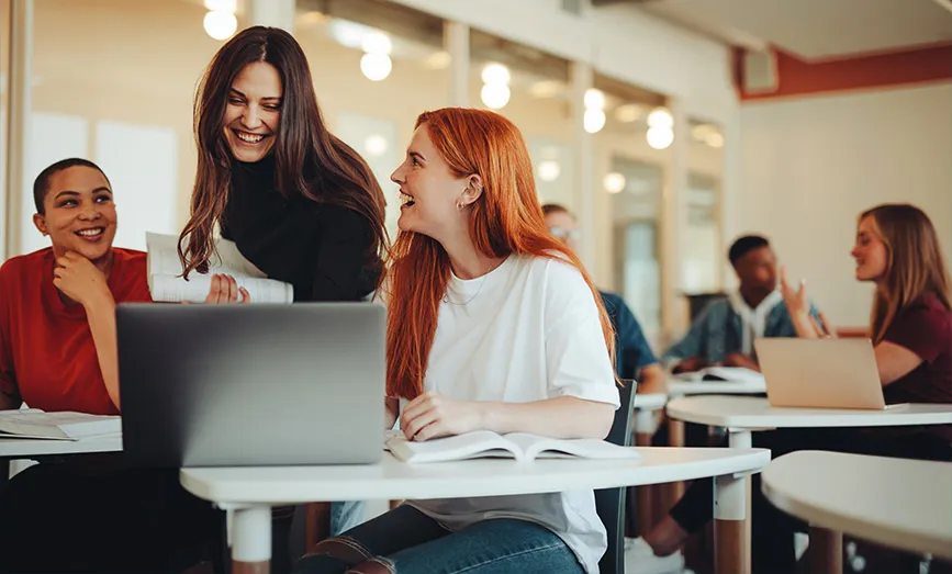 Three people gathered around a laptop computer
